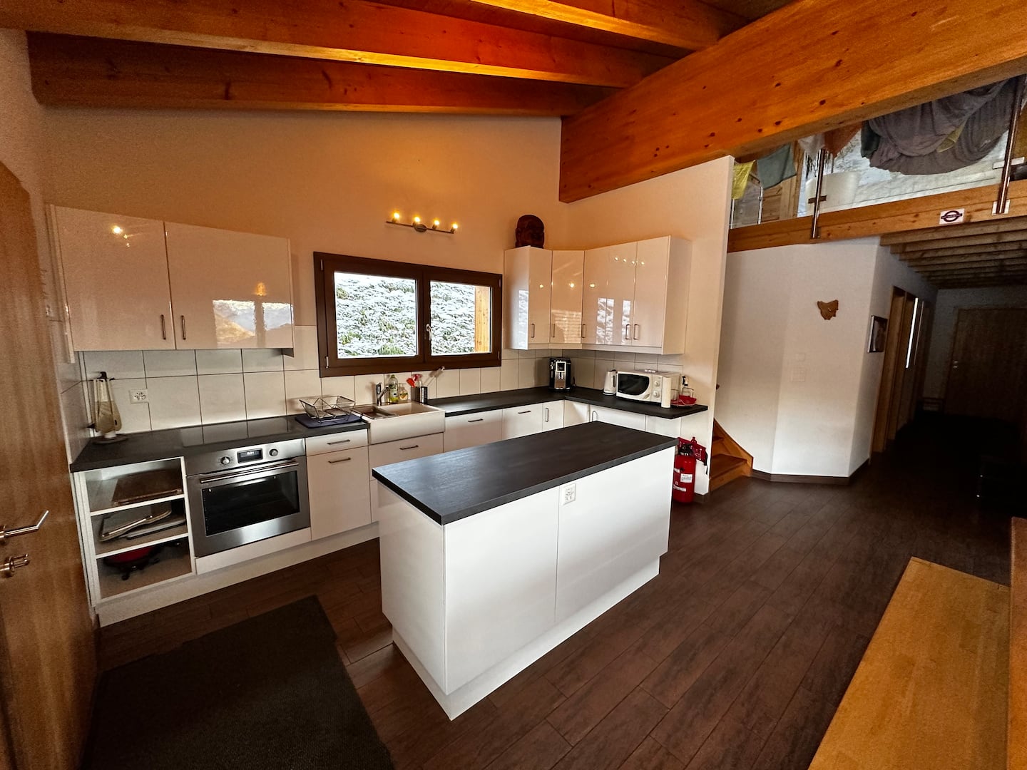 Open chalet kitchen with wooden beams and a large island used as the shared work table