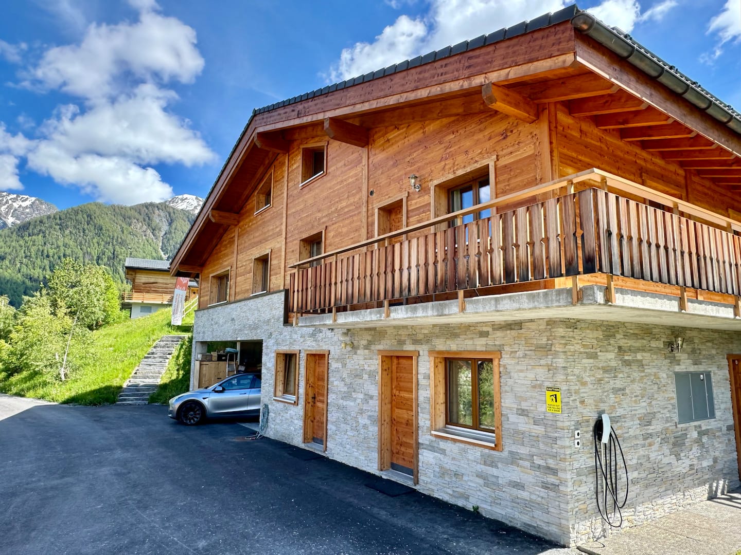 Exterior of the wooden chalet with balcony and stone base under blue alpine sky